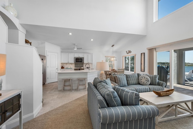 living area with baseboards, a high ceiling, a ceiling fan, and recessed lighting