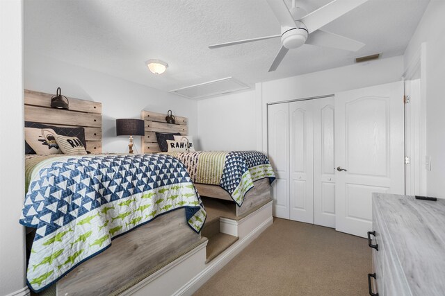 bedroom featuring attic access, visible vents, a textured ceiling, carpet floors, and a closet