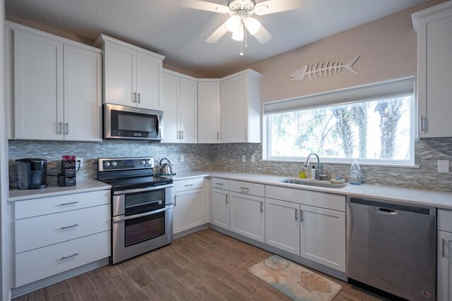 kitchen featuring appliances with stainless steel finishes, white cabinets, light countertops, and a sink