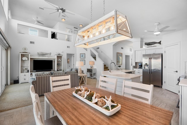 dining area with ceiling fan, a high ceiling, and visible vents