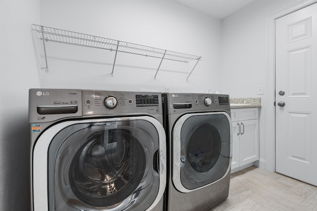 clothes washing area featuring washing machine and clothes dryer and cabinet space