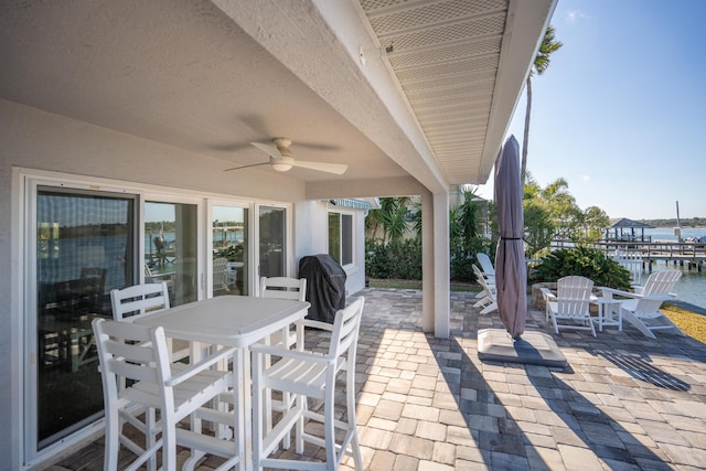 view of patio with a ceiling fan, outdoor dining area, a water view, and area for grilling