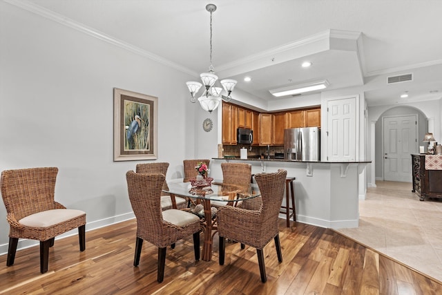 dining room with a chandelier, light wood-type flooring, and crown molding