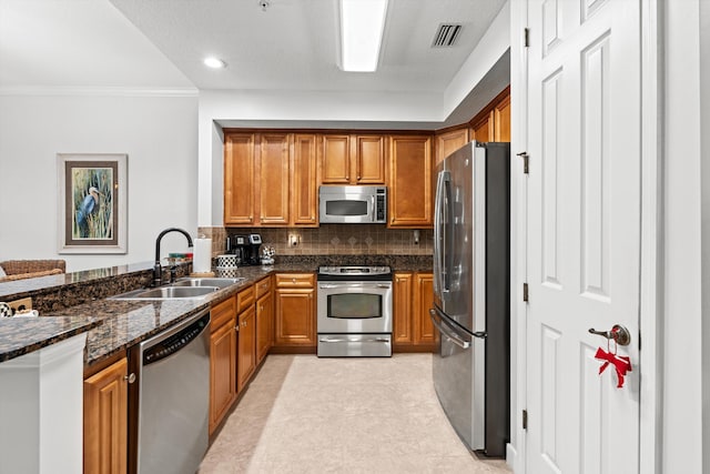 kitchen featuring crown molding, sink, dark stone countertops, tasteful backsplash, and stainless steel appliances