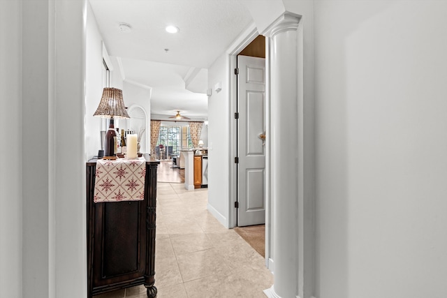 corridor with light tile patterned floors and decorative columns