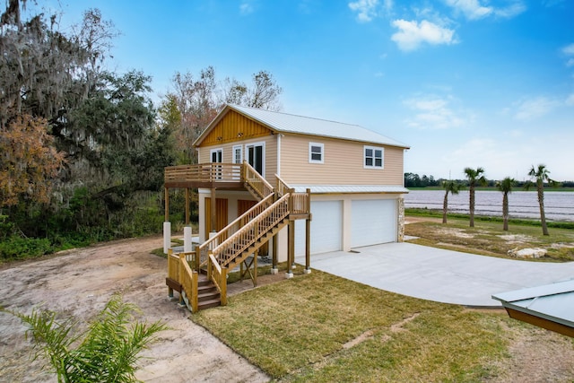 view of front of property with a garage, a water view, and a front lawn