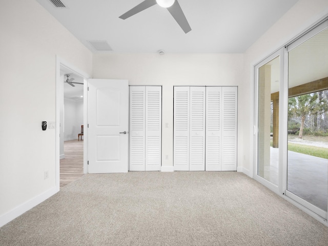 unfurnished bedroom featuring carpet, access to outside, ceiling fan, and two closets