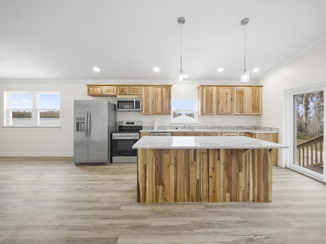 kitchen featuring ornamental molding, plenty of natural light, a kitchen island, pendant lighting, and stainless steel appliances