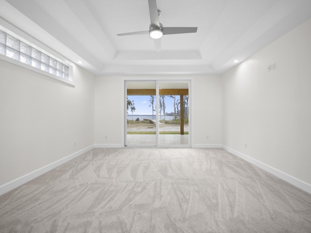 carpeted empty room featuring a tray ceiling and ceiling fan