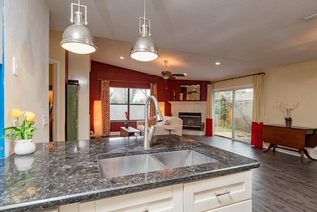 kitchen with dark stone countertops, a fireplace, a sink, dark wood-type flooring, and white cabinets