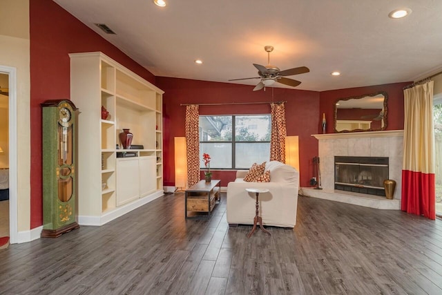 living room featuring dark wood-style floors, visible vents, recessed lighting, and a tile fireplace