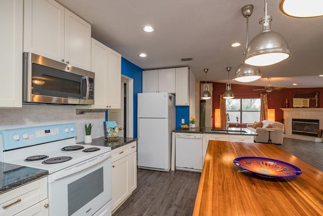 kitchen featuring wooden counters, dark wood finished floors, decorative backsplash, white appliances, and a sink