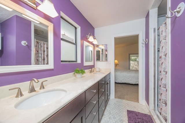 ensuite bathroom featuring double vanity, curtained shower, tile patterned floors, and a sink