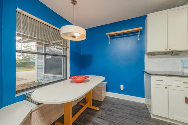 unfurnished dining area with dark wood finished floors and baseboards