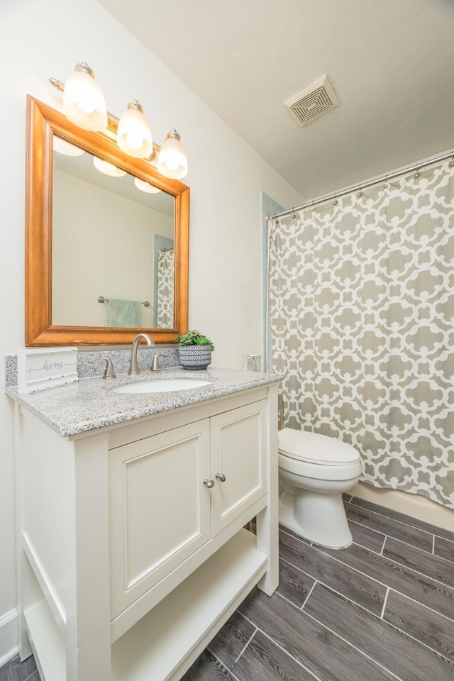 bathroom featuring visible vents, toilet, vanity, and wood finish floors