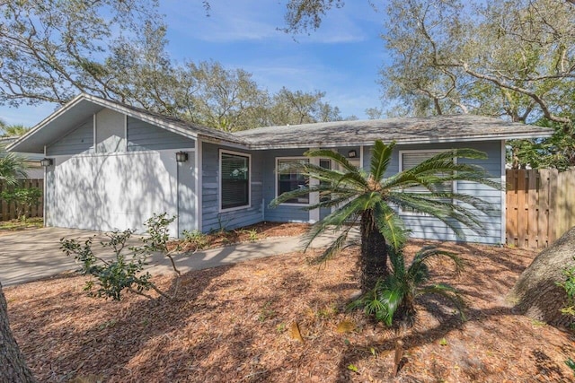 view of front of home with driveway, an attached garage, and fence