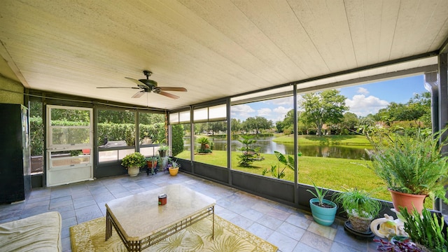 unfurnished sunroom featuring ceiling fan, plenty of natural light, and a water view