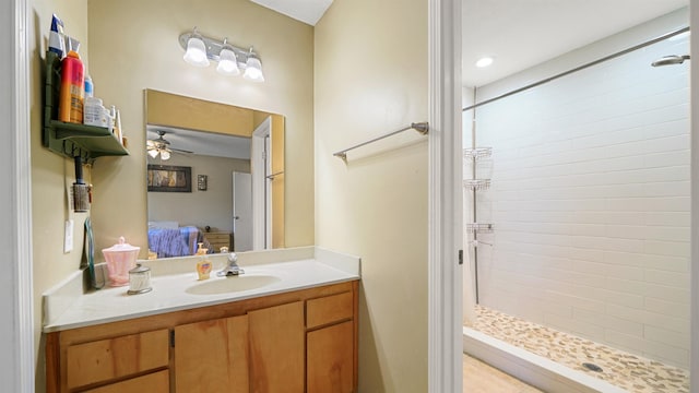 bathroom featuring ceiling fan, vanity, and tiled shower