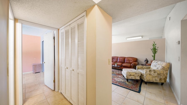 hall featuring light tile patterned floors and a textured ceiling