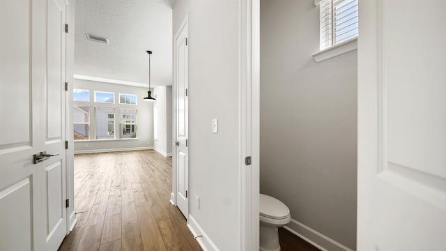 bathroom with hardwood / wood-style flooring, toilet, and a textured ceiling