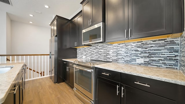 kitchen with sink, light stone countertops, appliances with stainless steel finishes, tasteful backsplash, and light hardwood / wood-style floors