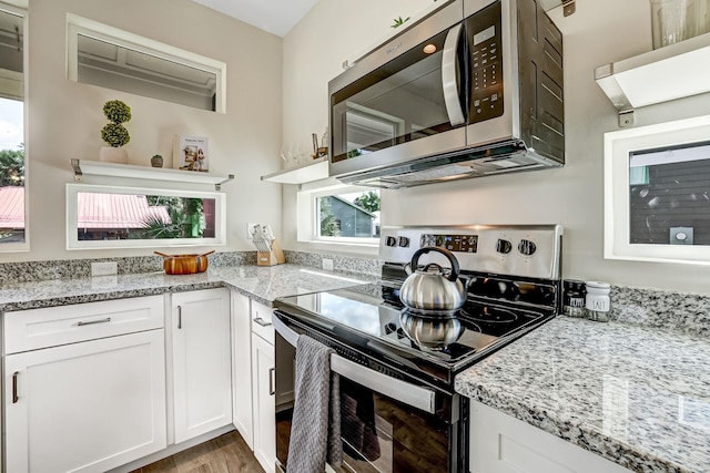 kitchen with white cabinets, light stone counters, light wood-type flooring, and stainless steel appliances