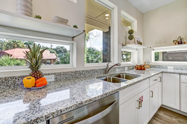 kitchen featuring dishwasher, white cabinets, sink, light stone countertops, and light hardwood / wood-style floors