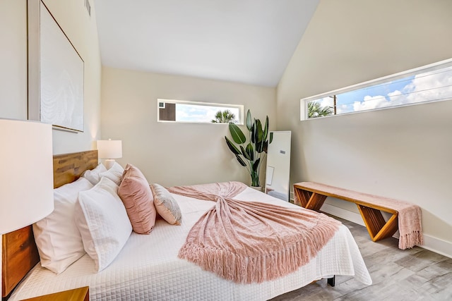 bedroom featuring light hardwood / wood-style floors, multiple windows, and lofted ceiling