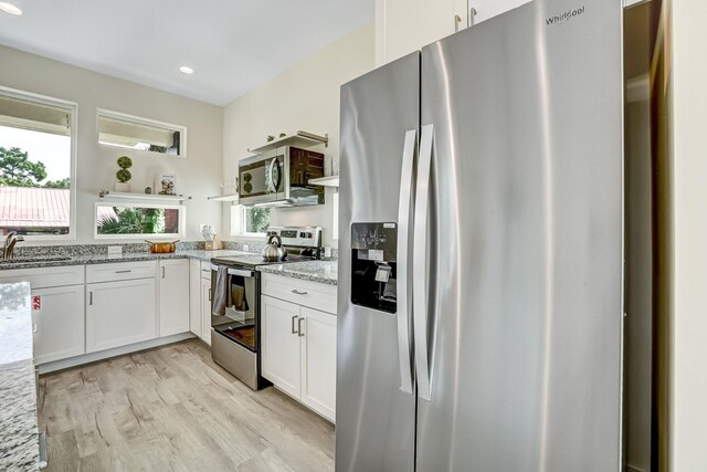 kitchen with white cabinets, appliances with stainless steel finishes, light hardwood / wood-style flooring, and plenty of natural light