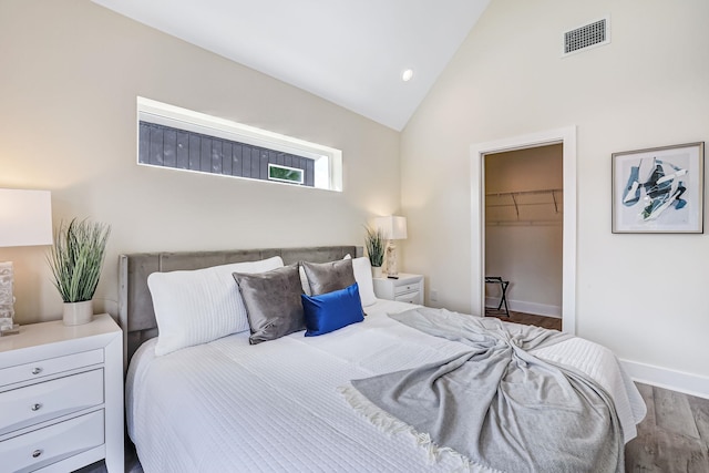 bedroom with a walk in closet, a closet, high vaulted ceiling, and hardwood / wood-style floors