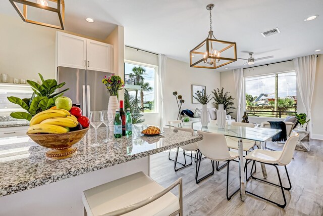 kitchen with a wealth of natural light, white cabinets, stainless steel refrigerator with ice dispenser, and light wood-type flooring