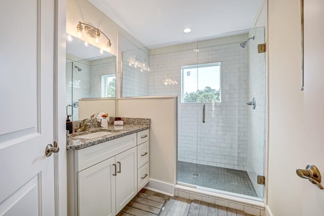 bathroom with hardwood / wood-style floors, vanity, a shower with door, and a healthy amount of sunlight