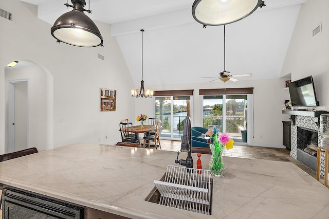 kitchen featuring high vaulted ceiling, beam ceiling, ceiling fan with notable chandelier, and hanging light fixtures