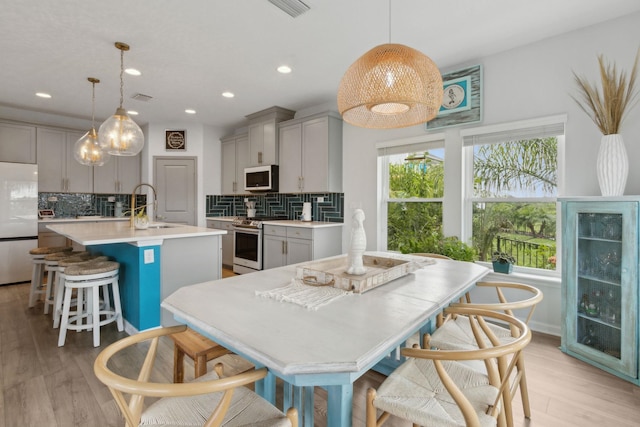 57 Guanahani Trl, Saint Augustine, FL 32080 - kitchen featuring stainless steel appliances, gray cabinetry, a kitchen island with sink, backsplash, and light countertops