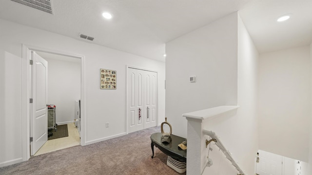 hall with light colored carpet