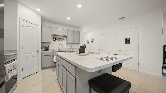 kitchen featuring a breakfast bar, sink, a kitchen island, and gray cabinetry