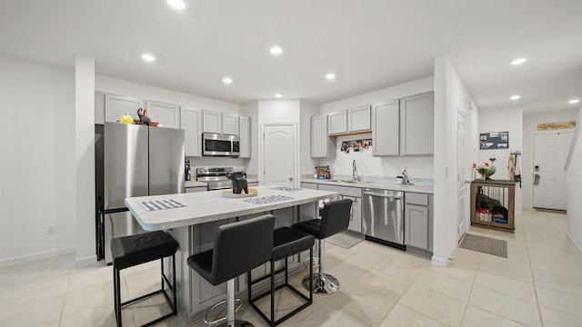 kitchen with a breakfast bar, stainless steel appliances, gray cabinets, and a kitchen island