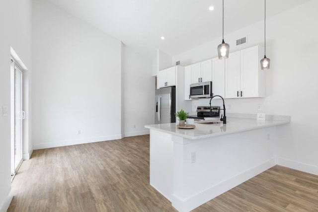 441 S Woodlawn St, Saint Augustine, FL 32084 - kitchen with appliances with stainless steel finishes, light wood-style flooring, light countertops, white cabinets, and decorative light fixtures