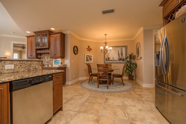 kitchen featuring stainless steel appliances, light stone counters, backsplash, crown molding, and pendant lighting