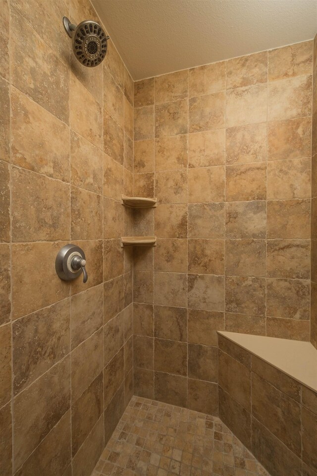 bathroom with tiled shower and a textured ceiling