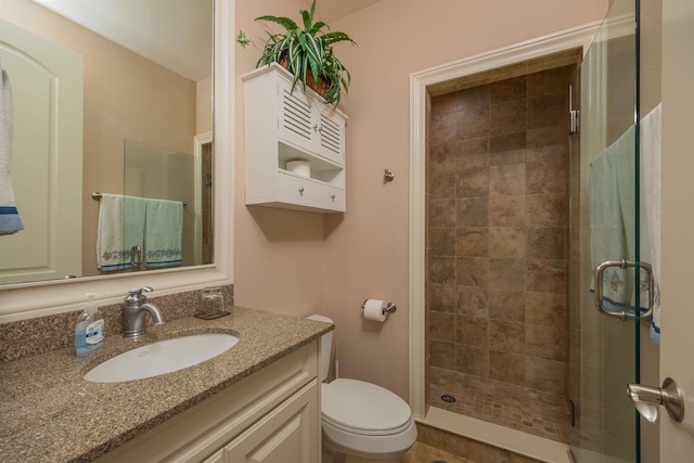 bathroom with vanity, toilet, and a shower with shower door