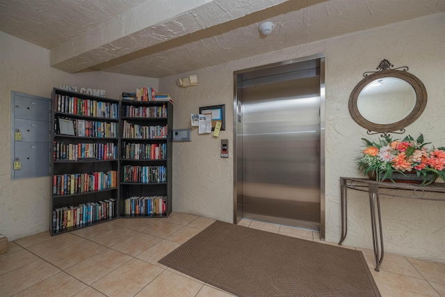 interior space featuring light tile patterned floors, a textured ceiling, and elevator