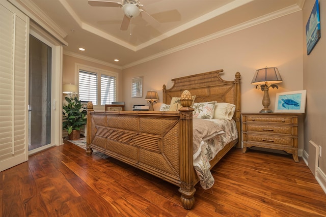 bedroom featuring dark hardwood / wood-style flooring, a tray ceiling, ceiling fan, and crown molding