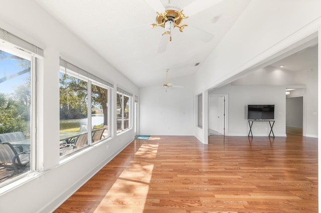 unfurnished sunroom featuring a healthy amount of sunlight, a ceiling fan, and vaulted ceiling