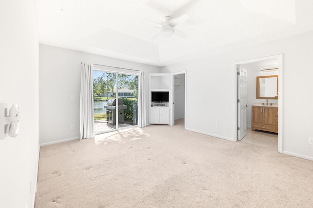 unfurnished bedroom featuring carpet flooring, access to outside, a sink, baseboards, and ensuite bathroom
