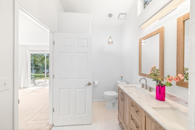 bathroom featuring a sink, toilet, double vanity, and tile patterned floors