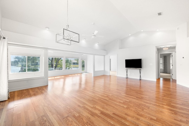 unfurnished living room with light wood-style floors, high vaulted ceiling, ceiling fan with notable chandelier, and visible vents