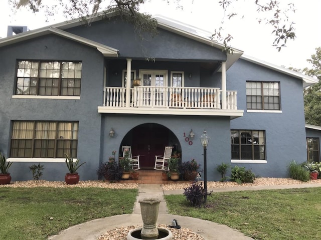 view of front facade featuring a balcony and a front yard