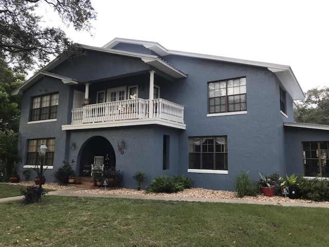 view of front of house with a balcony and a front yard