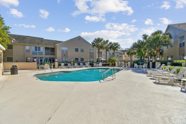 community pool featuring a patio, fence, and a residential view